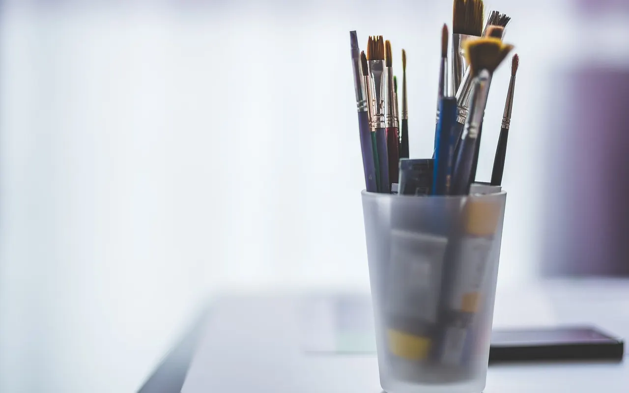 Farbtuben, Pinsel und Malutensilien auf einem Tisch
